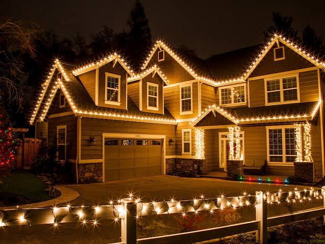 Christmas lights outlining a multi-story home and front fence